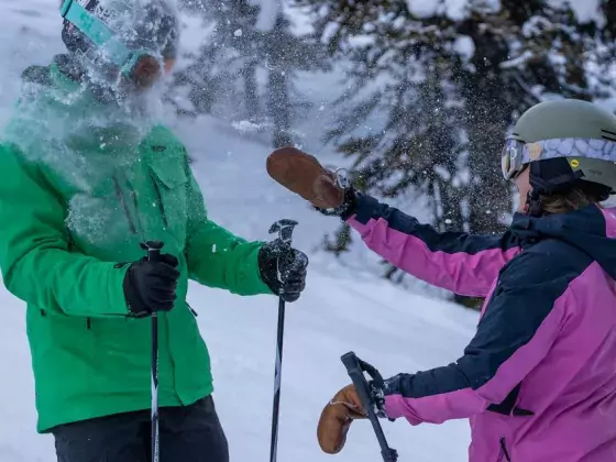 A women throwing a snowball at her friend on the ski hill